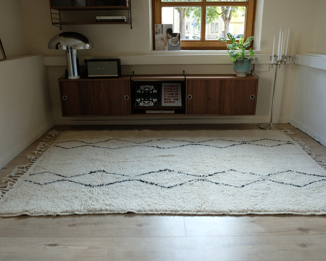 Nähere Ansicht desselben Raums, der Teppich reicht vom Sideboard bis an den Bildrand.