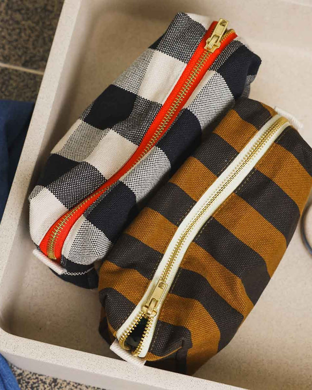 Kulturbeutel DESI Stripes Cumin in einer Ablage neben einem schwarz-weiß karierten Täschchen