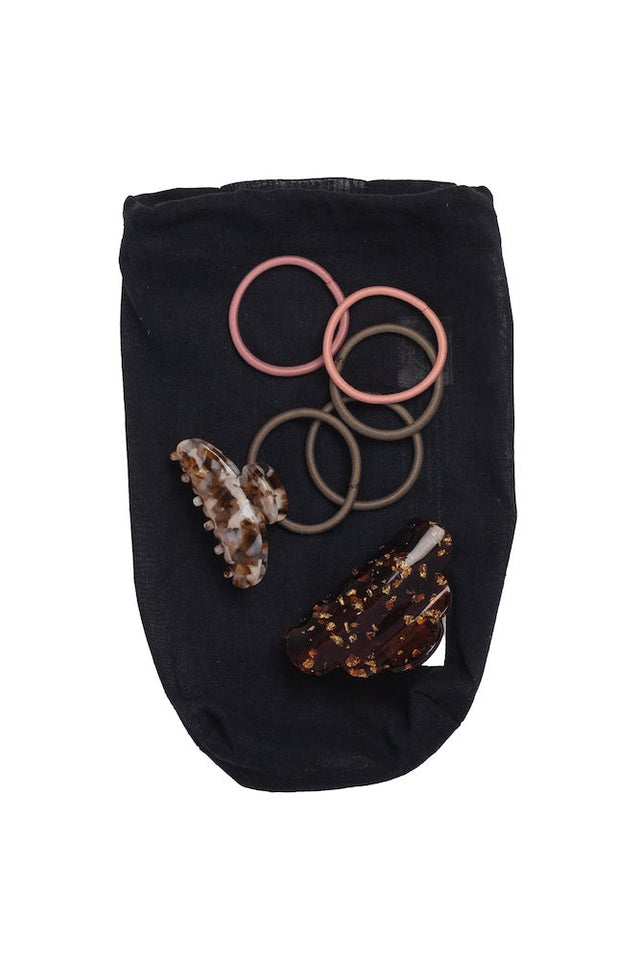 Flatlay des kleinsten Stoffbeutels aus Bio-Baumwolle mit Kordel in schwarz, zusammen mit Haargummis und Haarklammern.