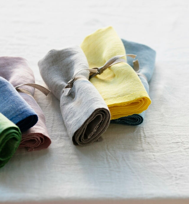 Aufgerollte Leinenservietten in vielen verschiedenen Farben auf dem Tisch