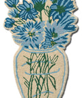 Wollteppich BLUE DAISY von Bongusta in Form einer Vase mit blauen Blüten und grünen Stielen, von oben auf Weiß
