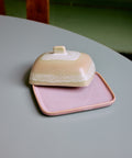 Butterdose SKYLINE auf einem hellblauen Tisch, der Deckel versetzt, die rosa Platte sichtbar