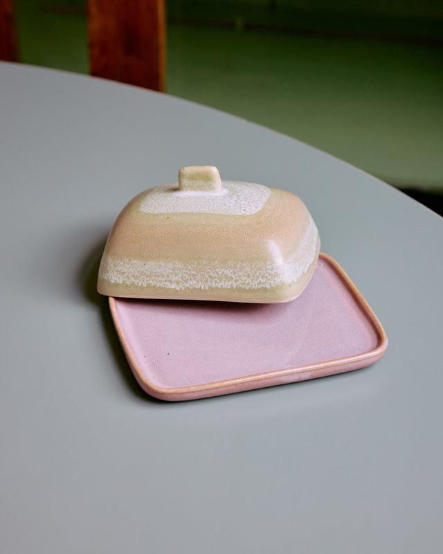 Butterdose SKYLINE auf einem hellblauen Tisch, der Deckel versetzt, die rosa Platte sichtbar