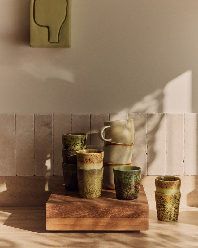 Teakholz-Sockel mit gestapelten Bechern aus der Reihe 70s Ceramics vor einer gefliesten Wand