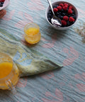 KESÄKUKKA Leinen-Tischdecke von oben, gedeckt mit Beeren und einem Glas Orangensaft