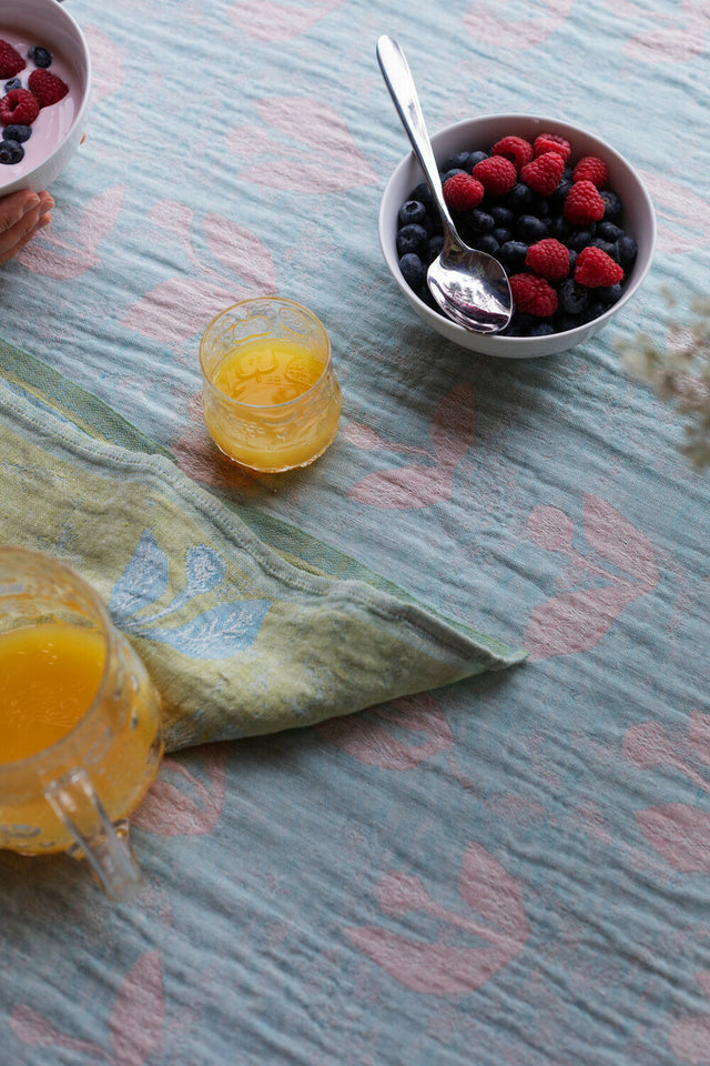 KESÄKUKKA Leinen-Tischdecke von oben, gedeckt mit Beeren und einem Glas Orangensaft