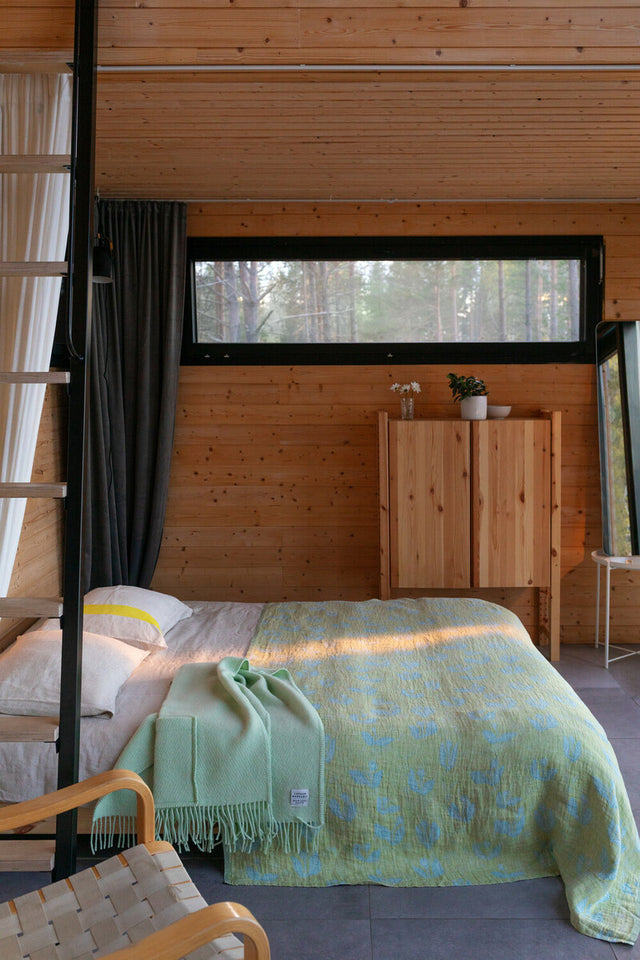 KESÄKUKKA Leinentuch als Überwurf auf dem Bett, darauf ein mintfarbener Wollschal