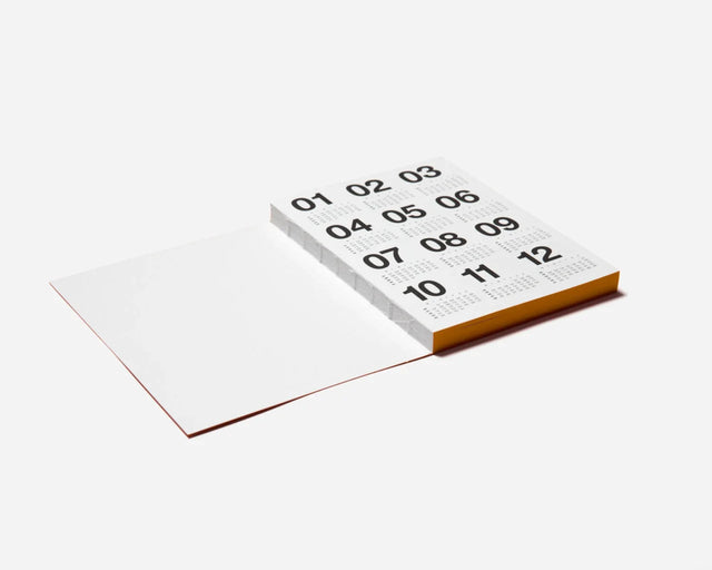 Basic Planner 2027 Karamell schräg aufgeschlagen, Jahresübersicht mit Monatszahlen und farbigem Seitenschnitt