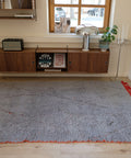 Berberteppich GREY RED 1,68 x 2,58 m im Raum: hellgrauer Flor mit roter Kante und roten Quasten