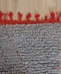 Teppichecke mit roter Einfassung und roten Quasten