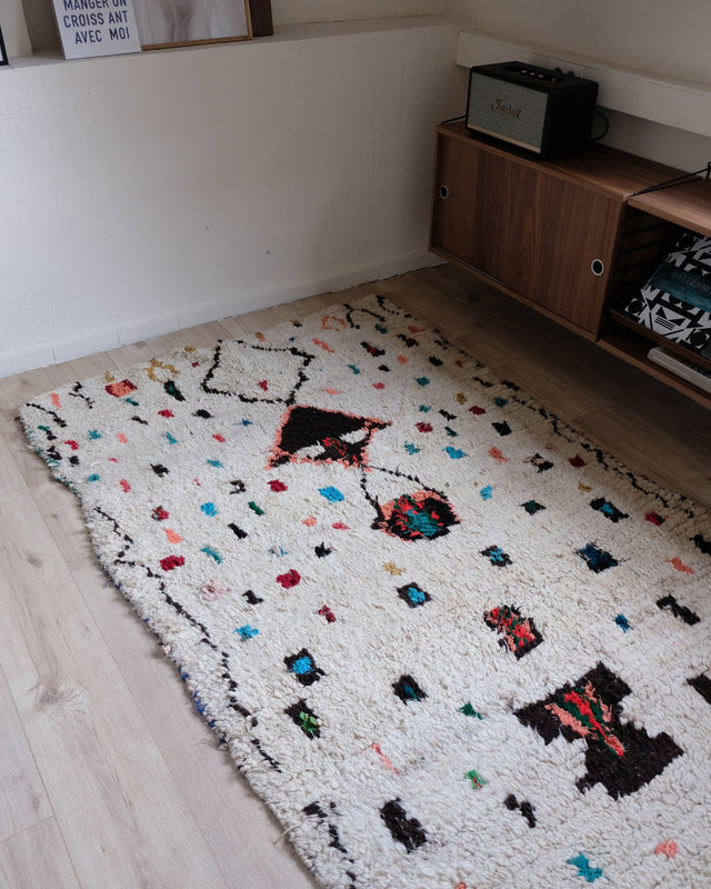 Langer Azilal mit bunten Tupfen von der Schmalseite aus gesehen, daneben ein Sideboard aus Holz