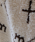 Detail: braunes Kreuz und kammartige Zeichen im dichten wollweißen Flor