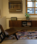Lila Boujad im Raum mit braunem Ledersessel, dahinter ein Fenster und ein Sideboard aus Holz