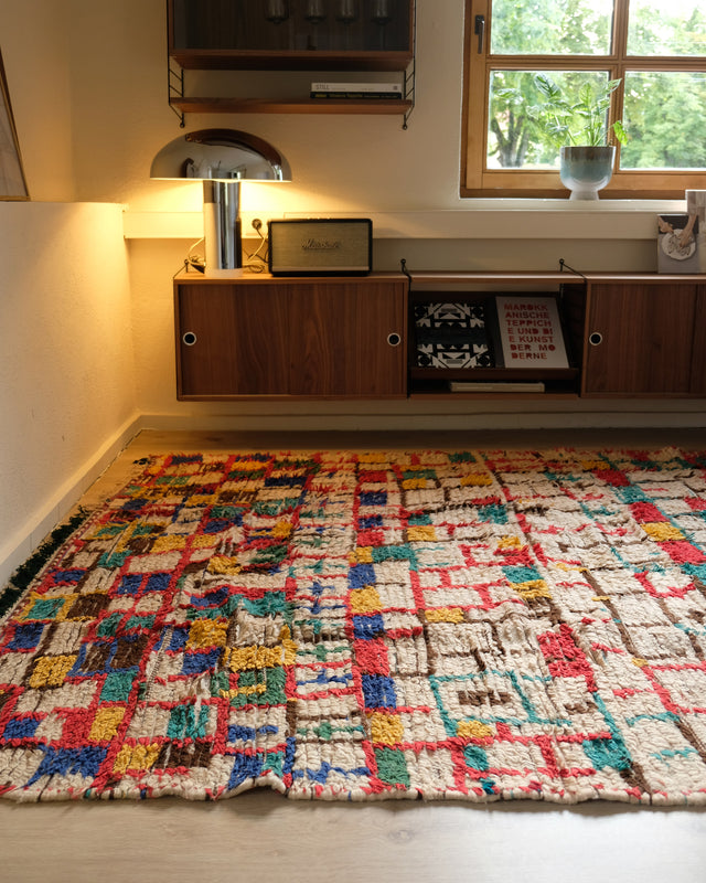 Vintage-Azilal-Teppich im Abendlicht, dahinter Wandregal mit Leuchte und Fenster