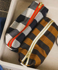Kulturbeutel DESI Stripes Cumin in einer Ablage neben einem schwarz-weiß karierten Täschchen