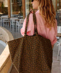 Frau im rosa Hemd mit der Tote Bag ELISA in Leo Olive über der Schulter in einem Café