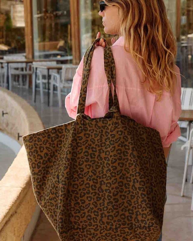 Frau im rosa Hemd mit der Tote Bag ELISA in Leo Olive über der Schulter in einem Café