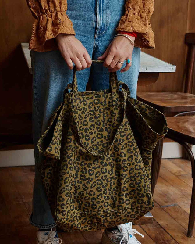 Tote Bag ELISA in Leo Olive, mit beiden Händen vor einer Jeans getragen