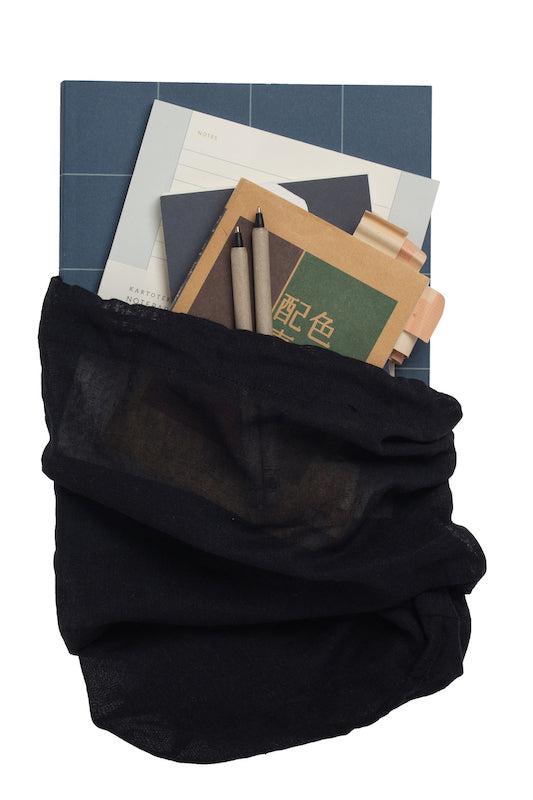 Großer Stoffbeutel aus Bio-Baumwolle in schwarz, gefüllt mit Büchern, Unterlagen und Schreibutensilien.