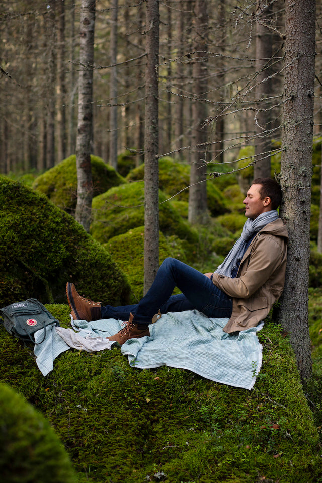 Mann auf Decke Maija in grün im Wald bei Ruhepause